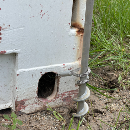 Steel ground anchor with steel cable looped to shipping container